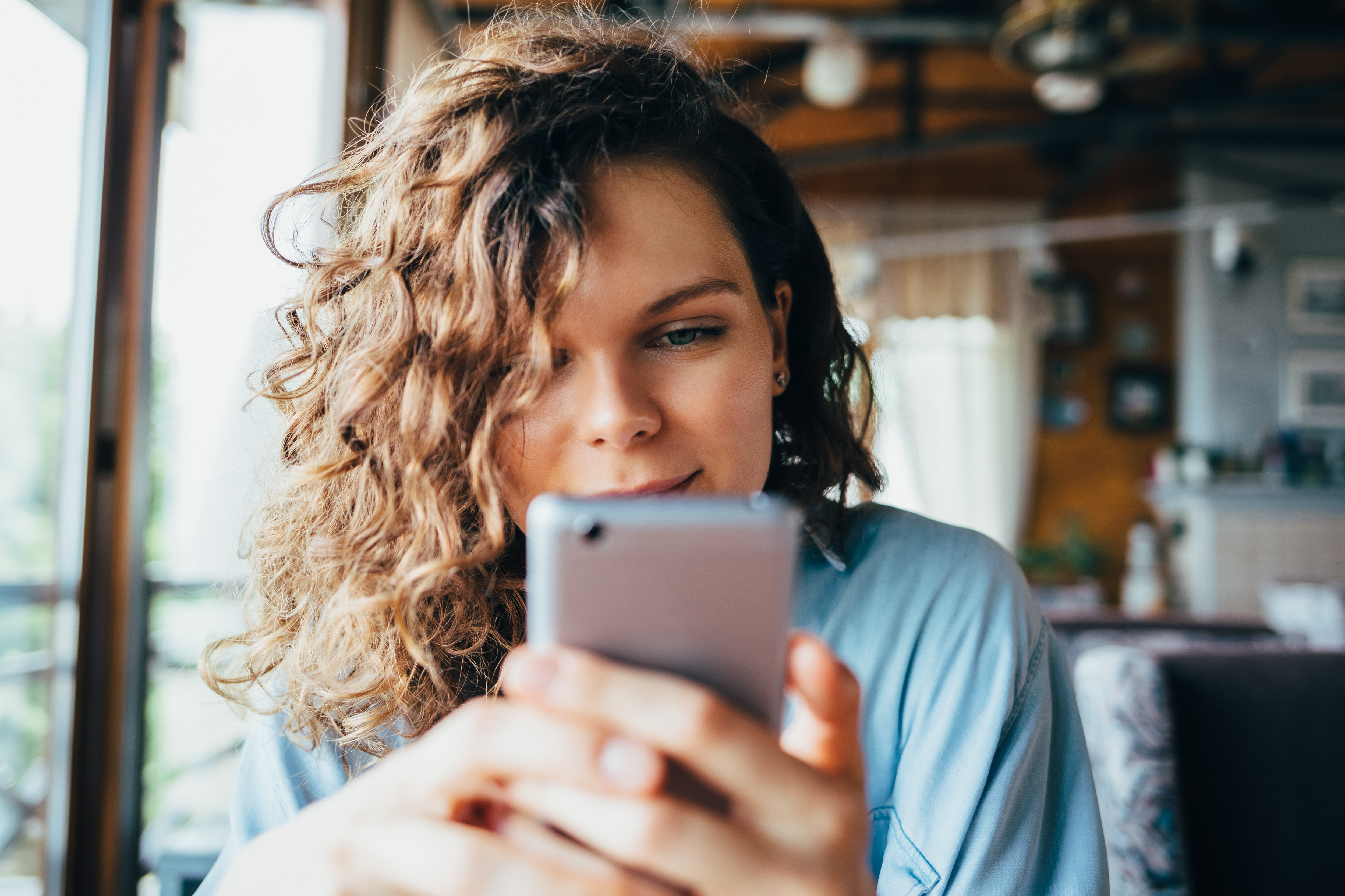 Mulher sorrindo enquanto cria conteúdo no celular